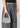 SUI AVA Mini Hobo Crystal Bag Clear Crystal, liten glitrende festveske med klare rhinsteiner og buet håndtak, båret av modell.