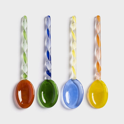 Skjesett med en grønn, en rød, en gul og en blå skje fra &Klevering. Alle skjeene har et spiralmønster med samme farge som skjeen i håndtaket.