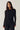 Modell iført Noella N-Madaline Top Black – sort langermet topp i transparent glitternett med avrundet hals og kroppsnær fasong.