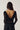Noella N-Madaline Top Black sett bakfra på modell – sort glitrende mesh-topp med lange ermer og elegant drapert fosseffekt i ryggen.