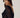 Modell stylet i Noella N-Madaline Top Black – langermet sort glitternetting-topp med transparent uttrykk og drapert rygg.