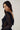 Modell stylet i Noella N-Madaline Top Black – langermet sort glitternetting-topp med transparent uttrykk og drapert rygg.
