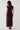 Modell sett bakfra i Noella N-Mignonette Dress Fig med draperte samlinger midt bak og myk velouroverflate.