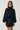 Modell med Noella N-Melda Dress Black, en kort sort satengkjole med lange voluminøse ermer og feminin, markert midje.