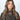 Modell med Small Triangle Scarf Brown fra Sui Ava – lite brunt strikket trekantskjerf knyttet tett rundt halsen.