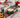Voluspa Noble Fir Garland duftlys i grønne glassbeholdere med dekorativt relieffmønster, stylet på julebord med Ornament Pedestal Candle, større duftlys og juledekorasjoner.