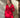 Modell i A-View Carrie Dress Red – rød, kort omslagskjole med glansfull satenglook, V-utringning, lange ermer og knytebelte i midjen. Kjolen har et asymmetrisk skjørt med dekorative volanger nederst og er stylet med sorte strømpebukser.