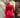 Modell sett bakfra i A-View Carrie Dress Red – kort, rød omslagskjole med glansfull satenglook, lange ermer, knytebelte i midjen og et utsvingt skjørt med volangkant nederst. Kjolen er stylet med sorte strømpebukser og en sølvfarget paljettveske.