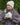 Modell utendørs med MSCH Copenhagen Hope Icon Beanie Oatmeal – lys beige, melert strikkelue med myk ribbestruktur og liten hvit logolapp foran. Luen er stylet med matchende beige strikkevotter og en brun, quiltet jakke med høy krage. Modellen holder en lys keramikkopp mellom hendene.