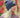 Modell utendørs med MSCH Copenhagen Hope Icon Beanie i melert blå – en myk strikkelue med bred oppbrettet kant og liten hvit logolapp foran. Luen er stylet med en chunky strikkegenser i rosa og burgundertoner.