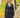 Modell i A-View Carrie Dress Black – sort, kort omslagskjole med lett glans, V-utringning, lange ermer og knytebelte i midjen. Kjolen har et asymmetrisk skjørt med dekorative volanger og er stylet med sorte strømpebukser og en sort paljettveske.