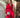 Modell i A-View Carrie Dress Red – kort, rød omslagskjole med glansfull satenglook, V-utringning, lange ermer og knytebelte i siden. Kjolen har et asymmetrisk skjørt med dekorative volanger og er stylet med sorte strømpebukser og en sølvfarget paljettveske.