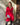 Modell i A-View Carrie Dress Red – kort, rød omslagskjole med glansfull satenglook, V-utringning, lange ermer og knytebelte i siden. Kjolen har et asymmetrisk skjørt med dekorative volanger og er stylet med sorte strømpebukser og en sølvfarget paljettveske.