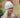 Modell utendørs med MSCH Copenhagen Hope Icon Beanie Oatmeal – myk, lys beige melert strikkelue med ribbestrikk, bred oppbrettet kant og hvit logolapp foran. Luen er stylet med en rosa og burgunder melert strikkegenser.