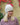 Modell utendørs med MSCH Copenhagen Hope Icon Beanie Oatmeal – myk, lys beige melert strikkelue med ribbestrikk, bred oppbrettet kant og hvit logolapp foran. Luen er stylet med en rosa og burgunder melert strikkegenser.