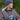 Modell utendørs med MSCH Copenhagen Hope Icon Beanie i melert blå, en myk strikkelue med bred oppbrettet kant og hvit logolapp foran. Luen er stylet med matchende blå strikkevotter og en brun, quiltet jakke. Modellen holder en blå keramikkopp mellom hendene.